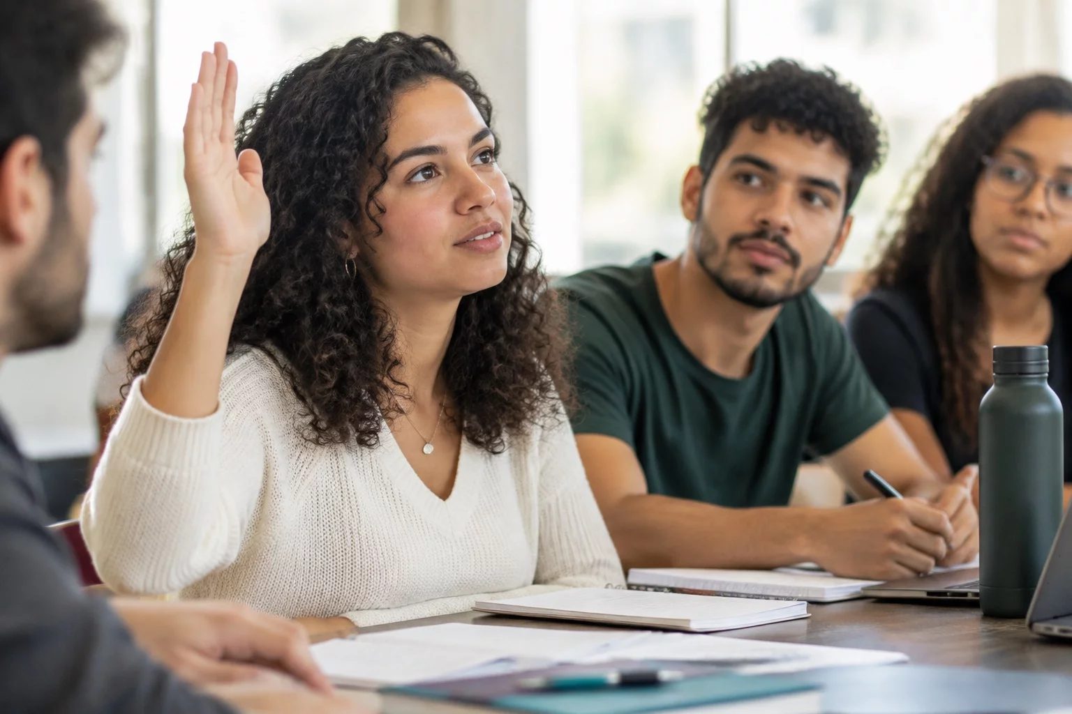 Estudante levantando a mão em uma mesa de seminário coberta de anotações